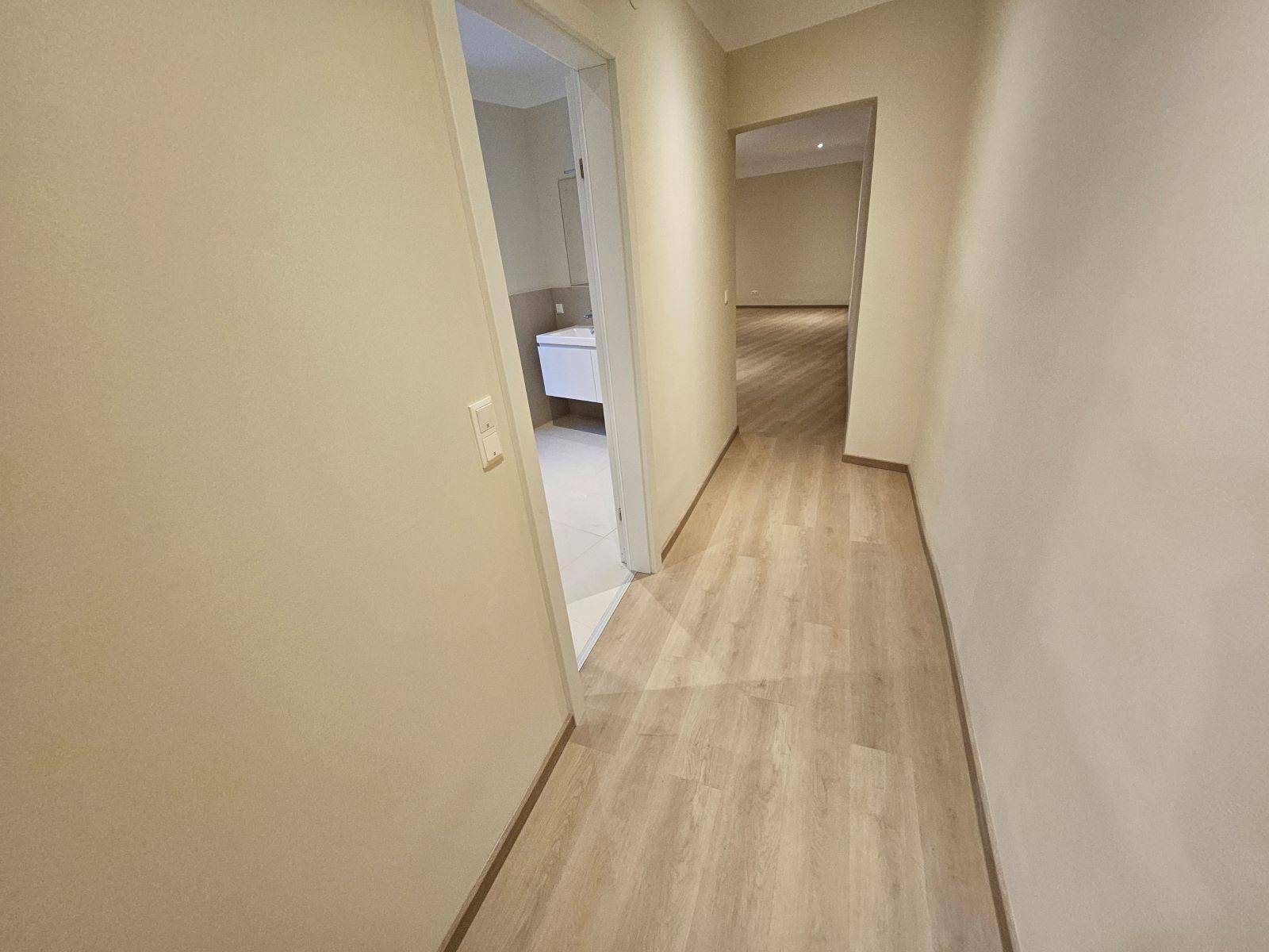 Heller Flur mit Laminatboden, der zu den verschiedenen Räumen der Wohnung führt.