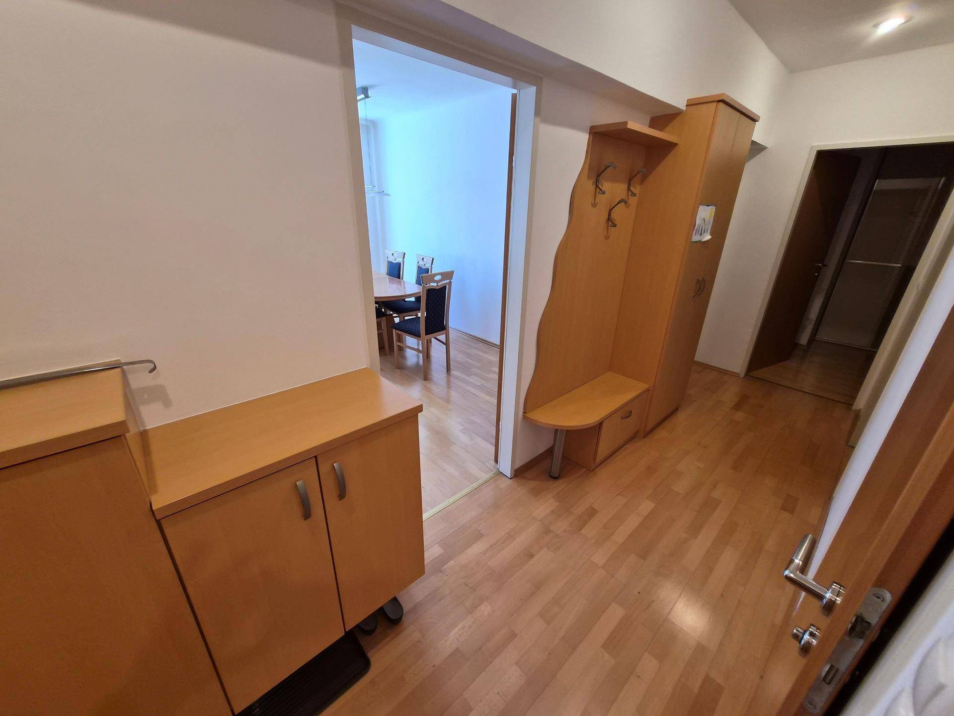 Heller Flur mit Garderobe und Holzmöbeln, der zum Essbereich führt.