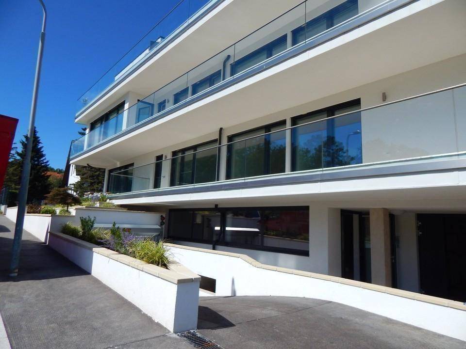 Moderne Gebäudefassade mit großen Fensterfronten und Zufahrt zur Tiefgarage des Wohnkomplexes.