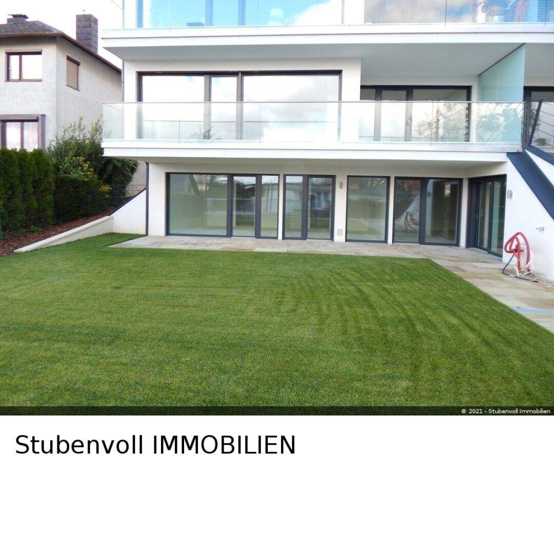 Moderne Gebäudefassade mit großen Fensterfronten und direktem Zugang zum grünen Garten.