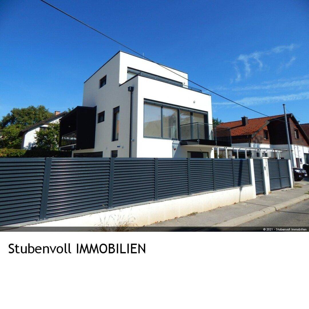 Moderne weiße Villa von der Straße aus gesehen mit stilvollem Zaun.