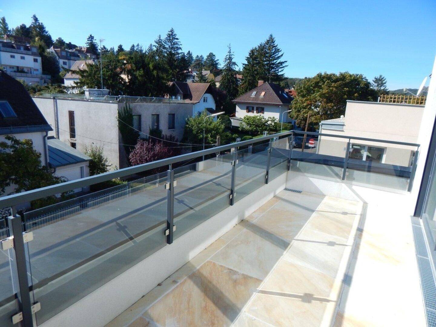 Geräumige Terrasse mit Glasgeländer und weitem Blick über die Umgebung.