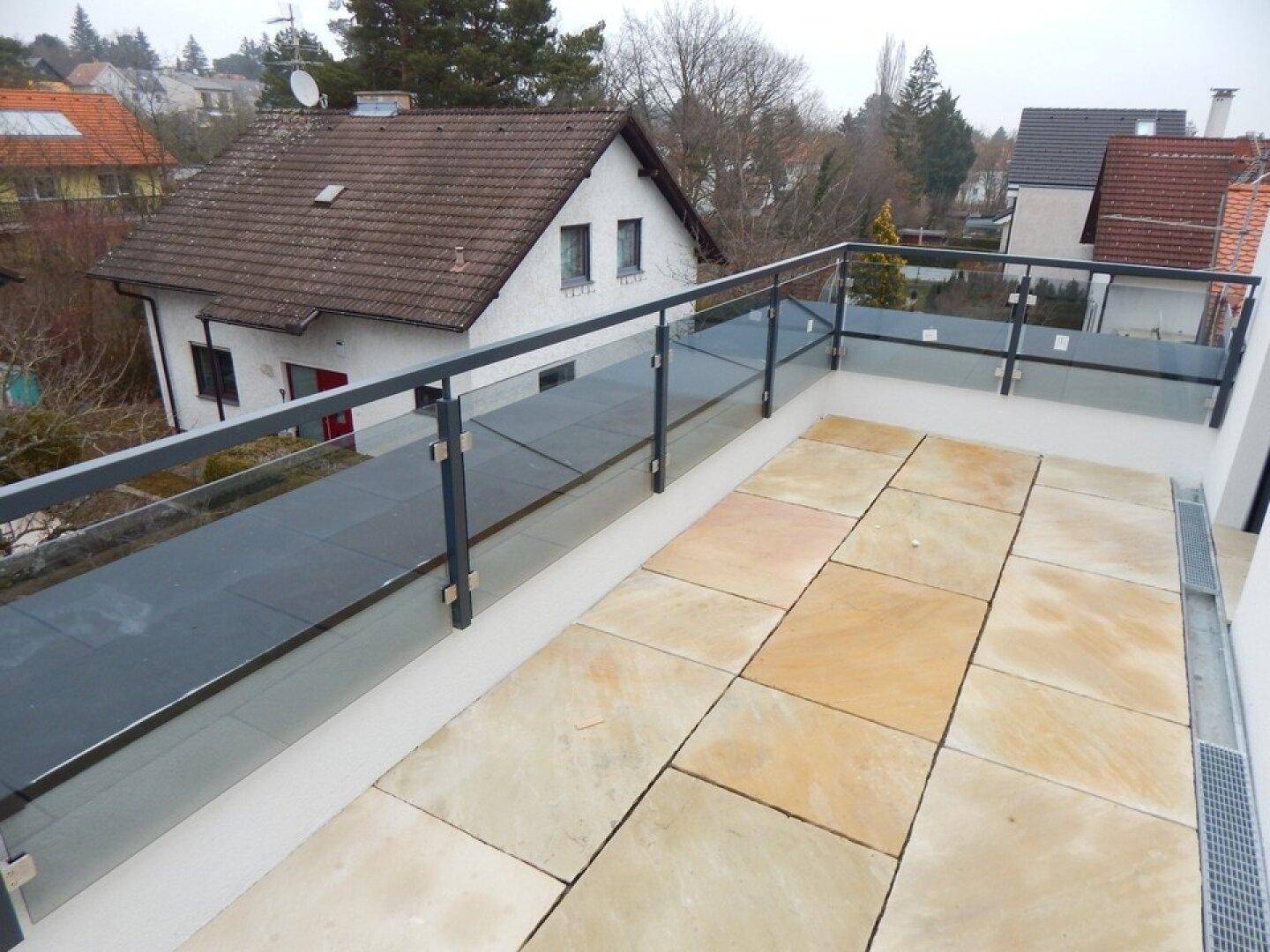Große Terrasse mit Glasgeländer und Panoramablick über die winterliche Wohngegend.