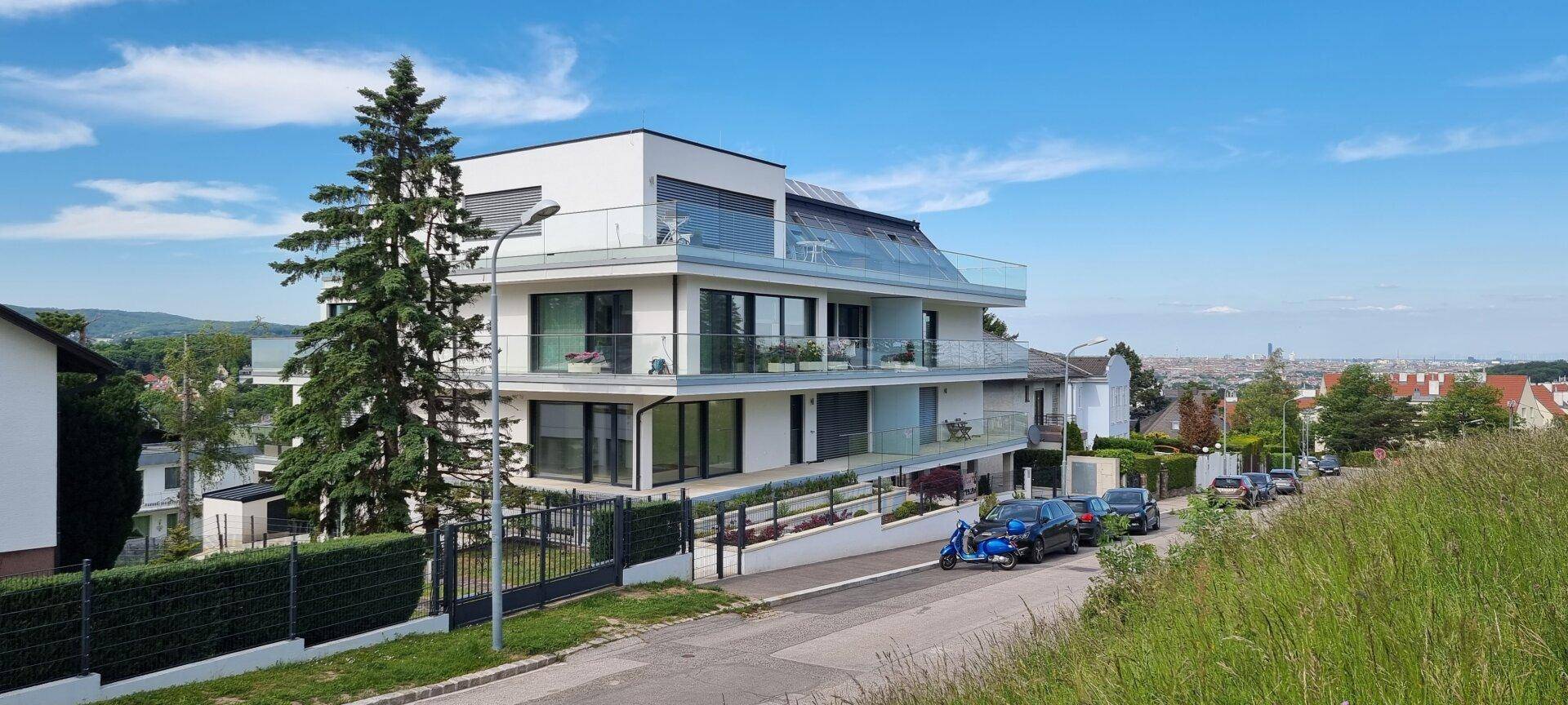 Modernes Wohngebäude mit mehreren Etagen, Balkonen und Blick auf die grüne Umgebung.