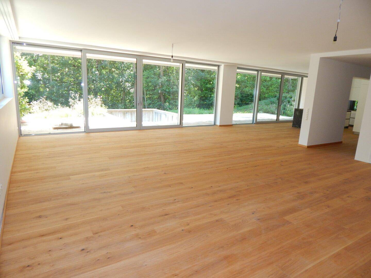 Helles, geräumiges Zimmer mit großen Fenstern und Holzboden, bietet viel natürliches Licht und Blick ins Grüne.