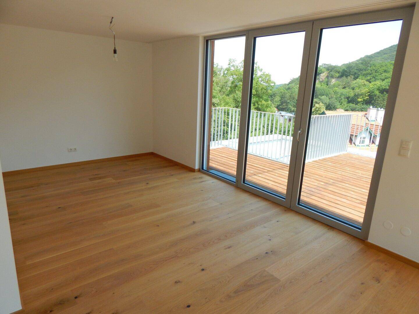 Helles Zimmer mit Holzboden und Zugang zu einem Balkon, bietet einen schönen Ausblick.