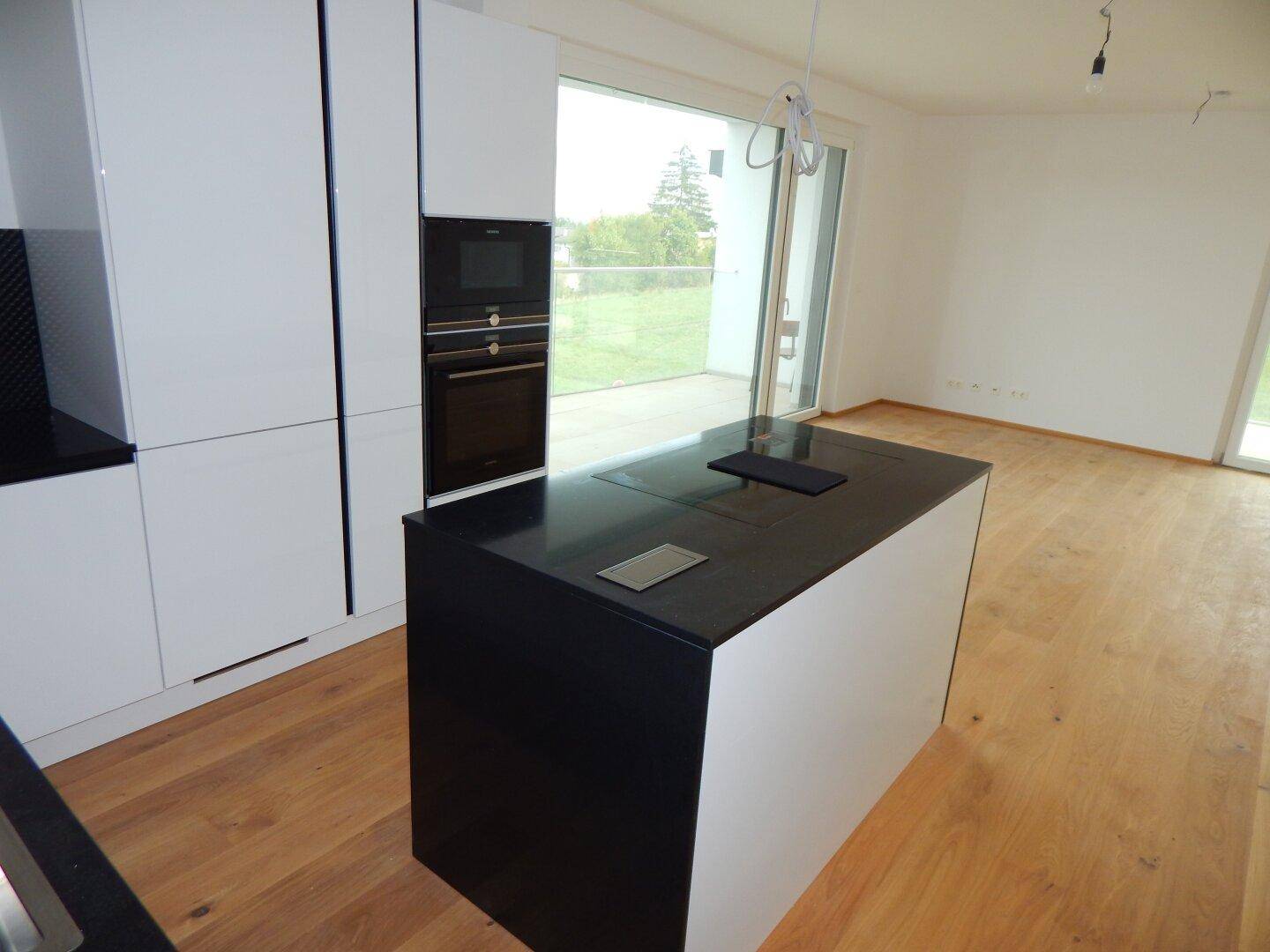 Offener Küchenbereich mit Kochinsel und Blick auf den angrenzenden Wohnraum.