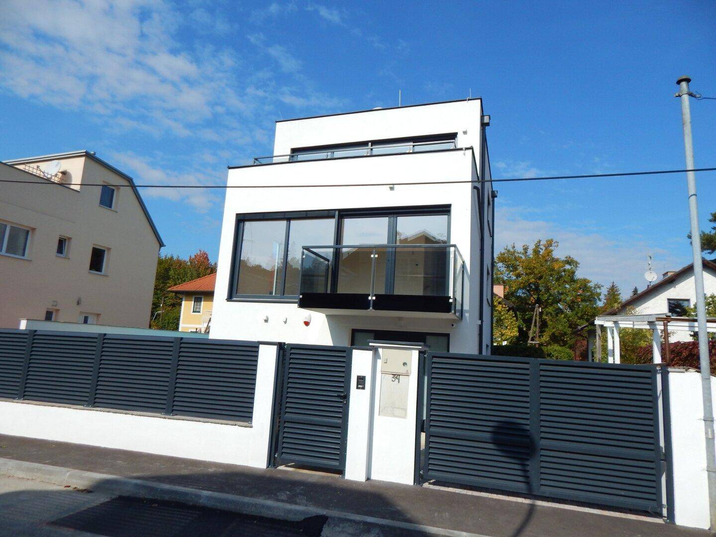 Die moderne Fassade des Hauses mit großen Fenstern und einem eleganten Eingangsbereich.