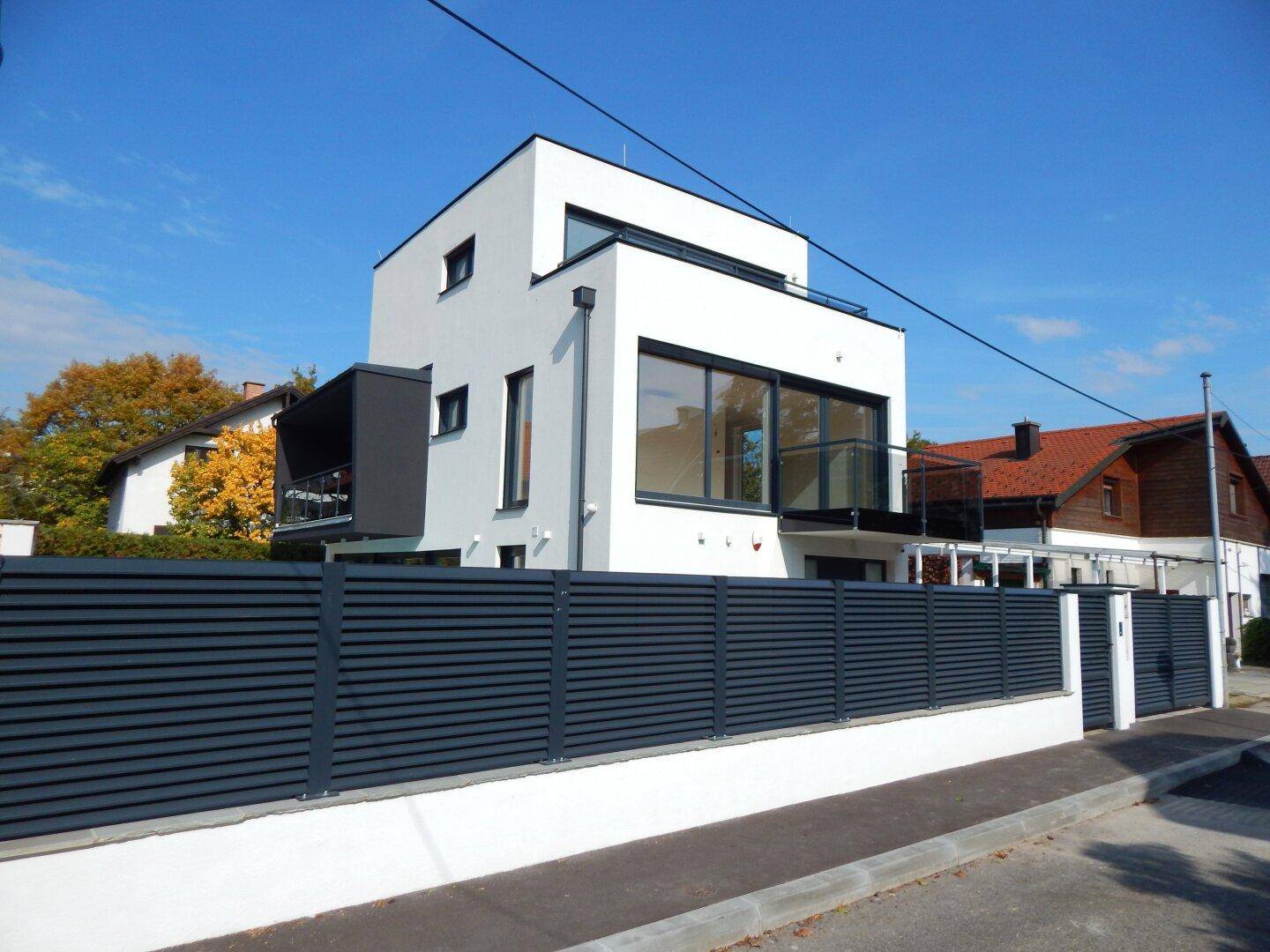 Ansicht des modernen Wohnhauses von der Straßenseite mit elegantem Zaun und klarem Design.