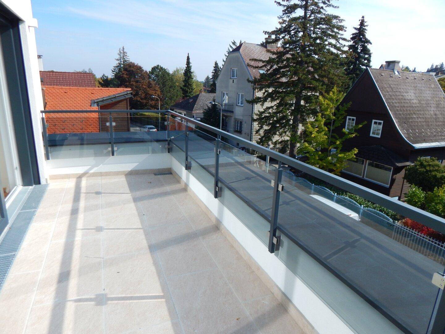 Geräumiger Balkon mit Glasgeländer bietet einen weiten Blick über die umliegende Nachbarschaft.