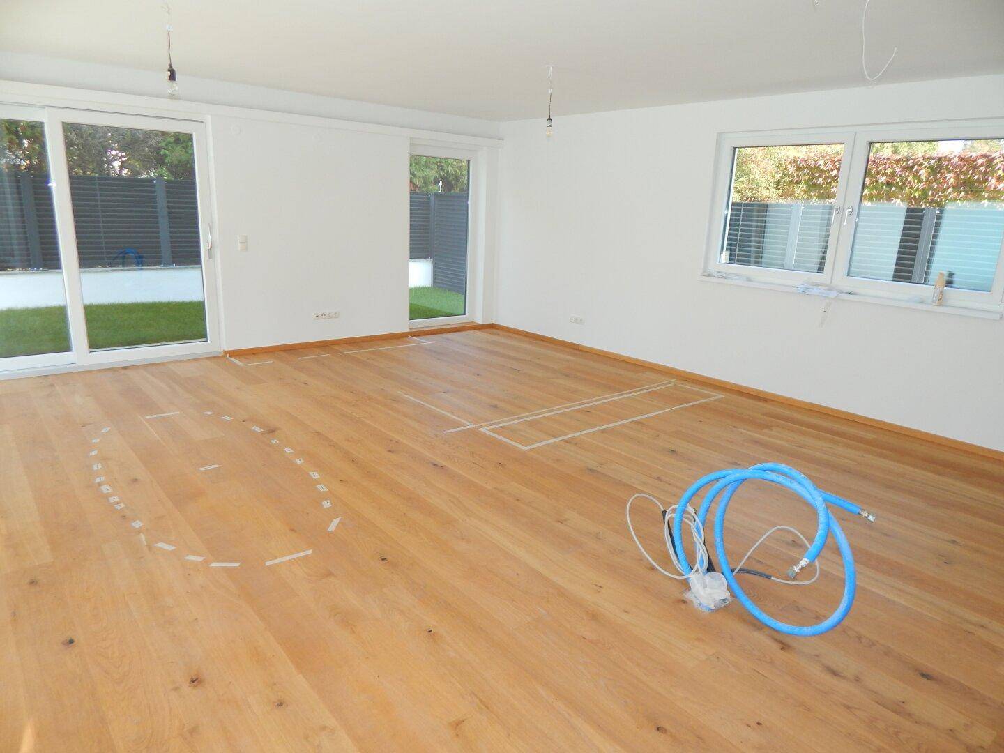 Helles Wohnzimmer mit neuem Holzparkettboden und großen Schiebetüren zum Garten und Pool.