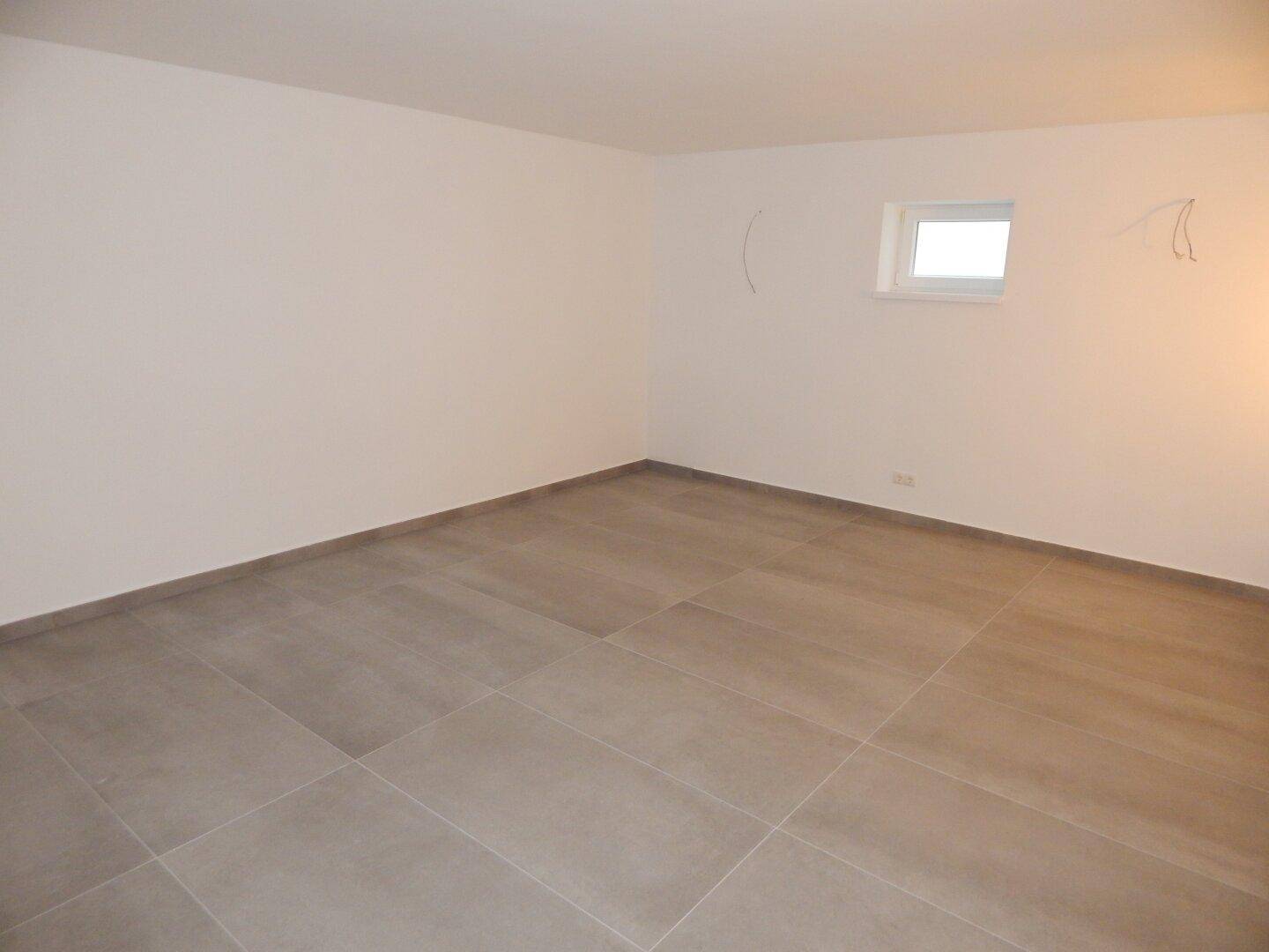 Leerer Raum mit neutralen Wänden und kleinem Fenster, bereit zur individuellen Gestaltung.