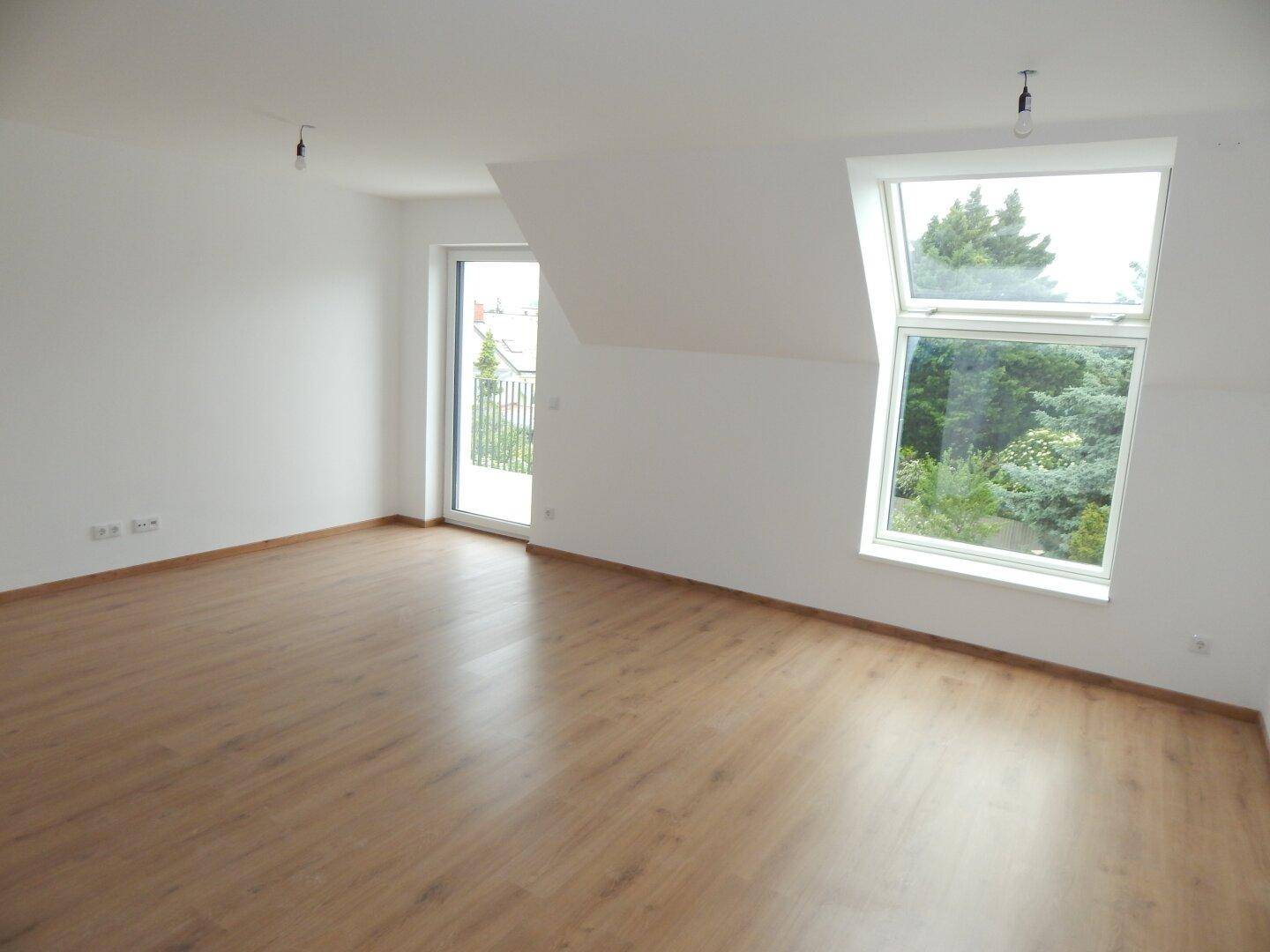Geräumiges Zimmer mit viel Tageslicht, Laminatboden und Dachschrägenfenster.