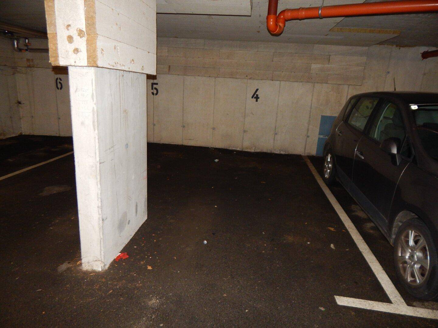Tiefgaragenstellplatz mit einem geparkten Auto und Betonpfeilern.