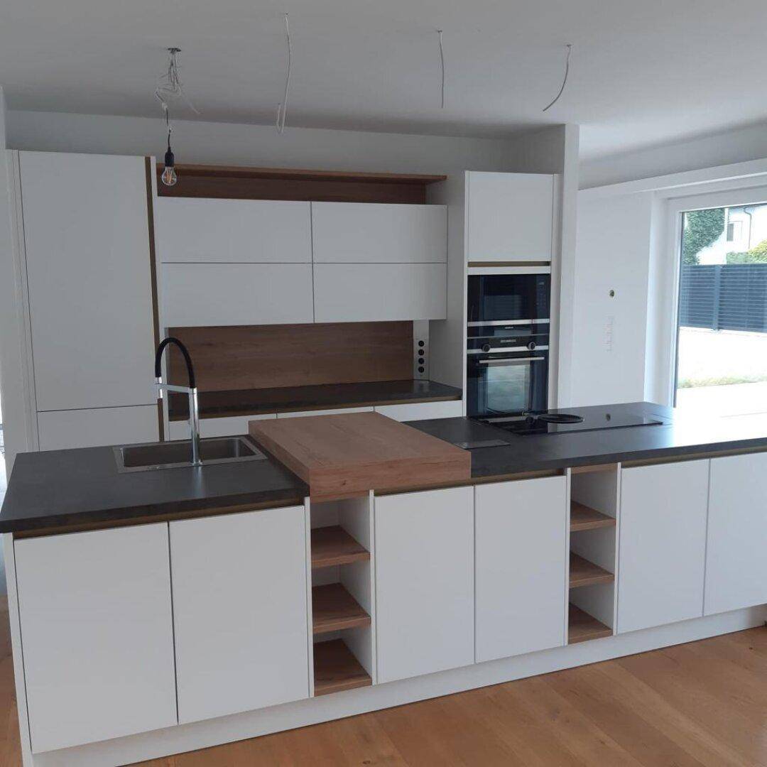 Moderne Einbauküche mit Kücheninsel, Spüle und Induktionskochfeld in hellem Design.