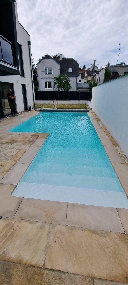 Langer Swimmingpool mit breiter Steinterrasse, ideal zum Entspannen und Schwimmen.