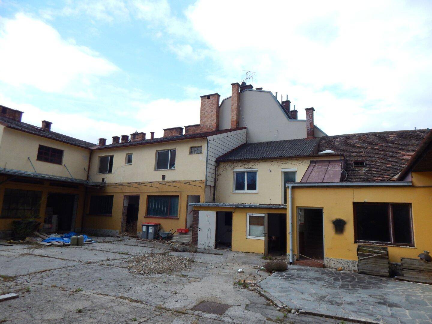 Gebäudekomplex mit Innenhof, verschiedenen Fenstern und einem bewölkten Himmel.