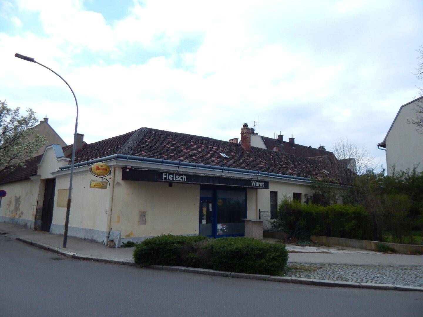 Eckansicht des Gebäudes mit einem Geschäft im Erdgeschoss und einem Laternenpfahl.
