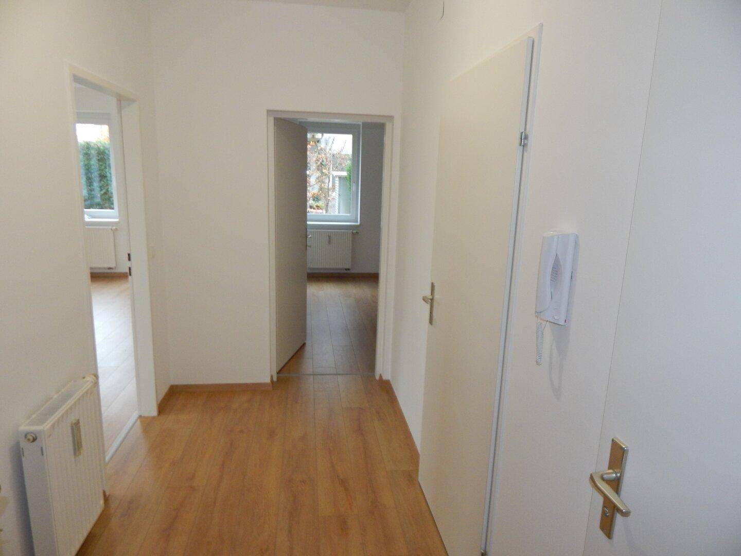 Heller Flur mit Laminatboden und weißen Türen, der zu weiteren Zimmern führt.