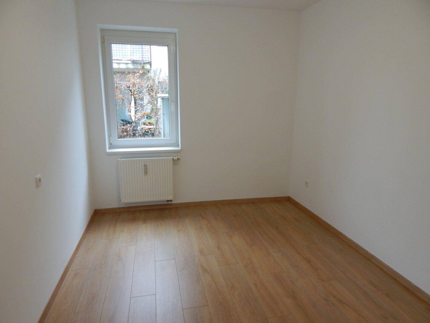Kleineres, helles Zimmer mit Laminatboden und einem Fenster, ideal als Schlaf- oder Arbeitszimmer.