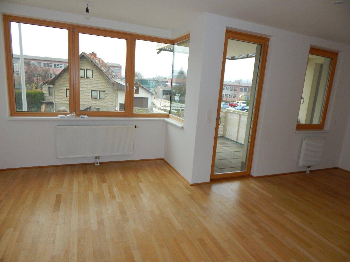 Geräumiges, helles Zimmer mit Parkettboden und großen Fenstern mit Blick auf die Umgebung.