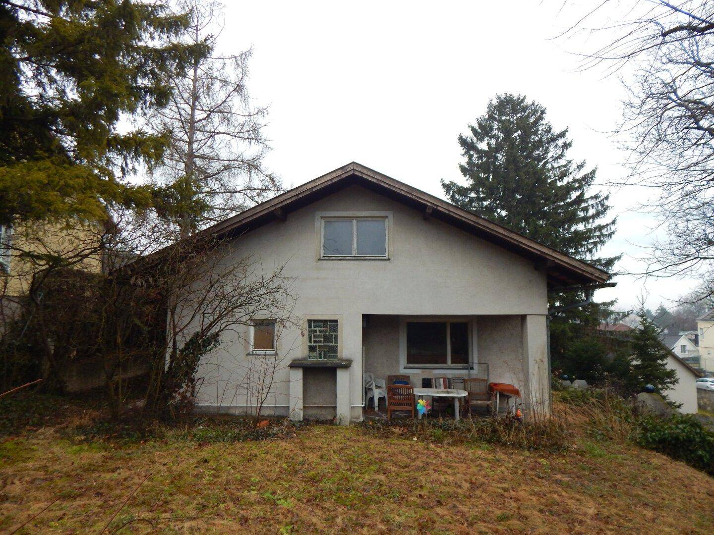 Rückansicht des Hauses mit überdachter Terrasse und Blick auf den Garten.