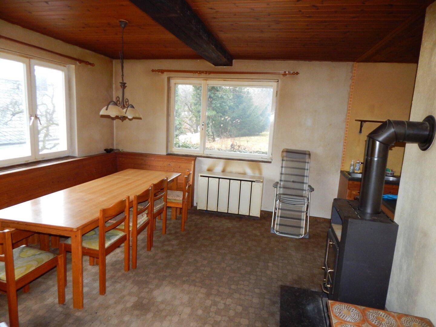 Rustikaler Essbereich mit Holztisch, Eckbank und Kaminofen, bietet eine warme Atmosphäre.