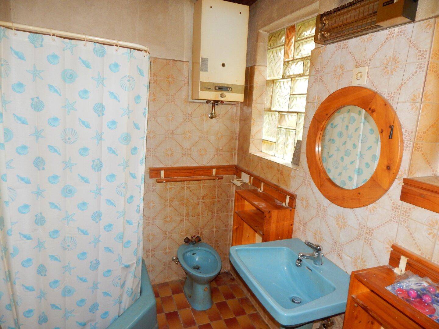 Badezimmer mit blauer Badewanne, Bidet und Fliesen im 80er-Jahre-Stil, benötigt Modernisierung.
