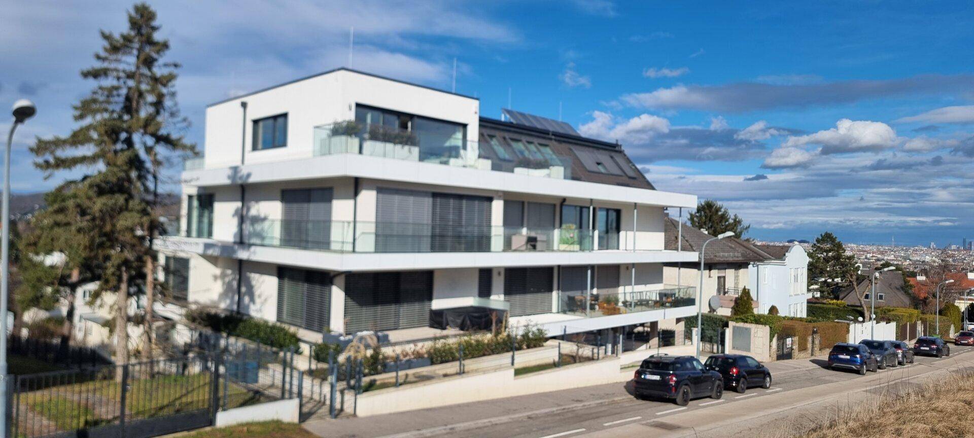 Modernes Wohnhaus mit mehreren Etagen, Balkonen und weitem Blick über die Stadt.