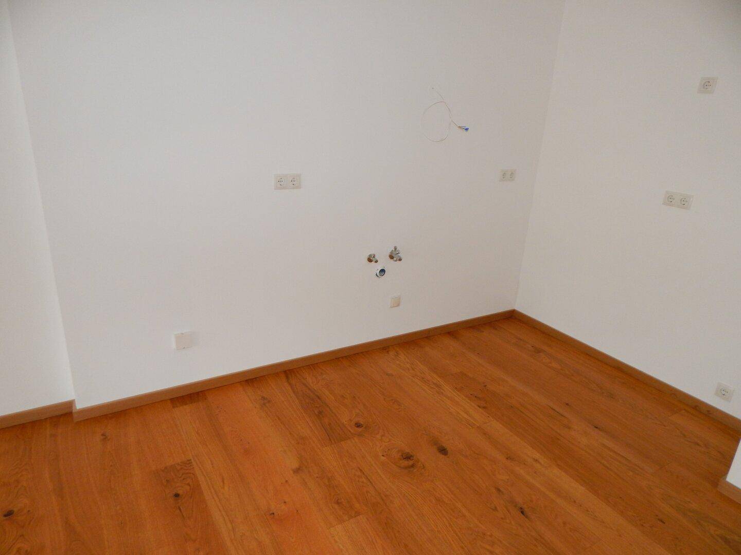 Leerer Raum mit Anschlüssen an der Wand, möglicherweise für eine Küche oder einen Hauswirtschaftsraum.
