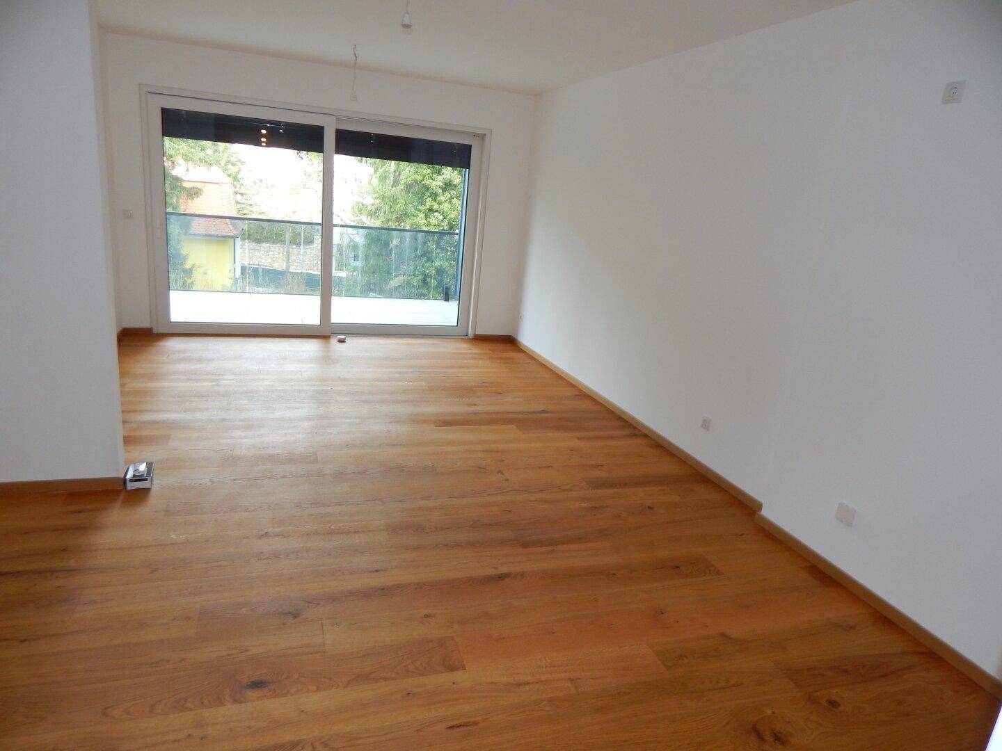 Geräumiges Wohnzimmer mit hellen Wänden und Holzboden, bereit zur individuellen Gestaltung.