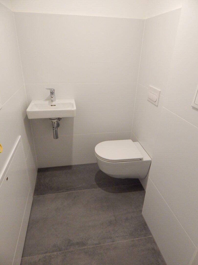 Kleines, funktionales Gäste-WC mit wandhängender Toilette und minimalistischem Waschbecken.