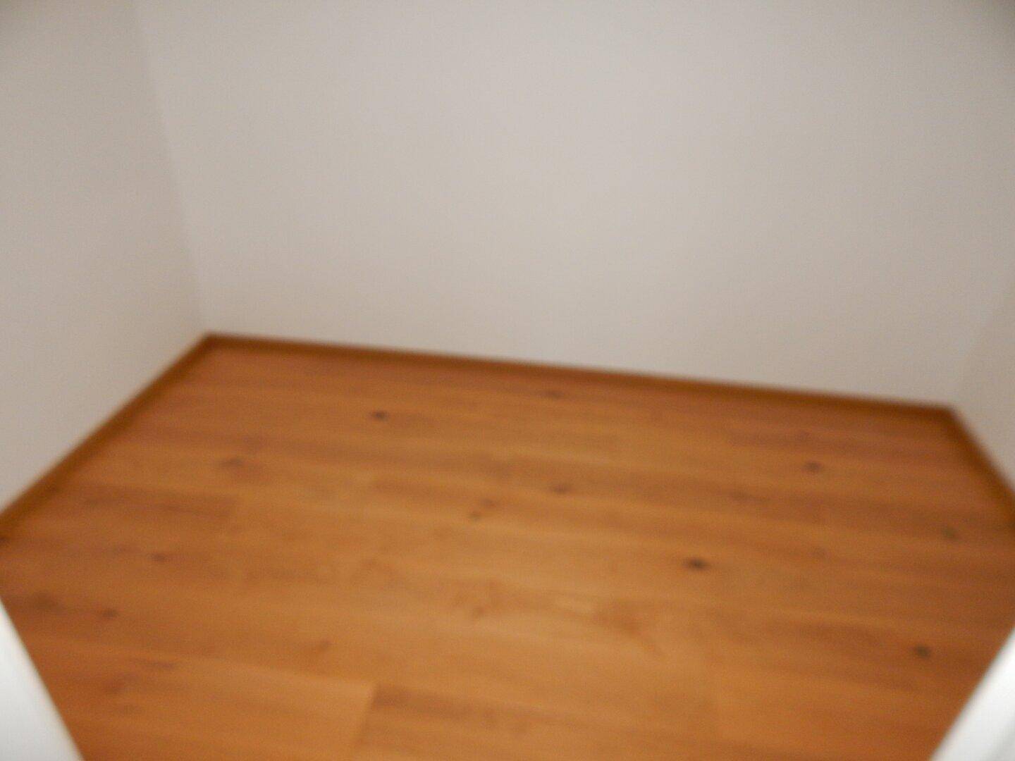 Kleiner, leerer Abstellraum mit Holzboden und weißen Wänden.