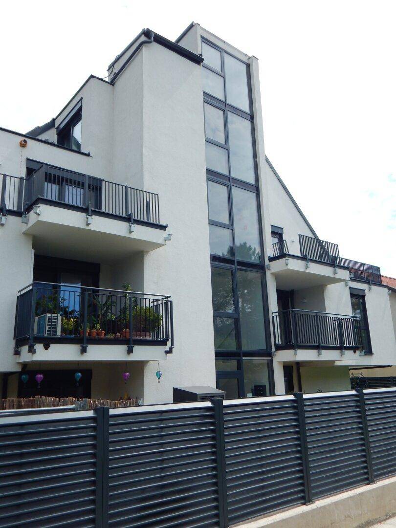 Detailansicht der modernen Gebäudefassade mit großen Glasflächen und Balkonen.