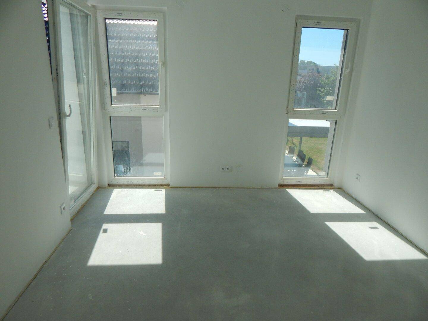 Heller, unmöblierter Raum mit zwei Fenstern und viel Tageslicht, noch im Bau.