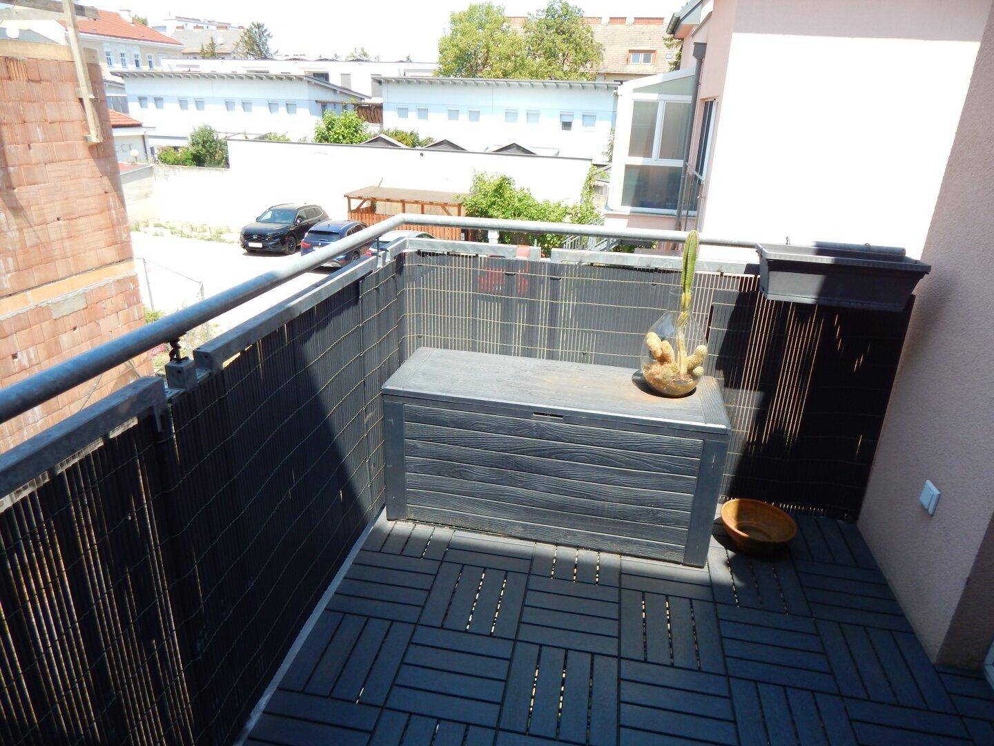 Balkon mit dunklen Bodenfliesen und einer Aufbewahrungsbox.