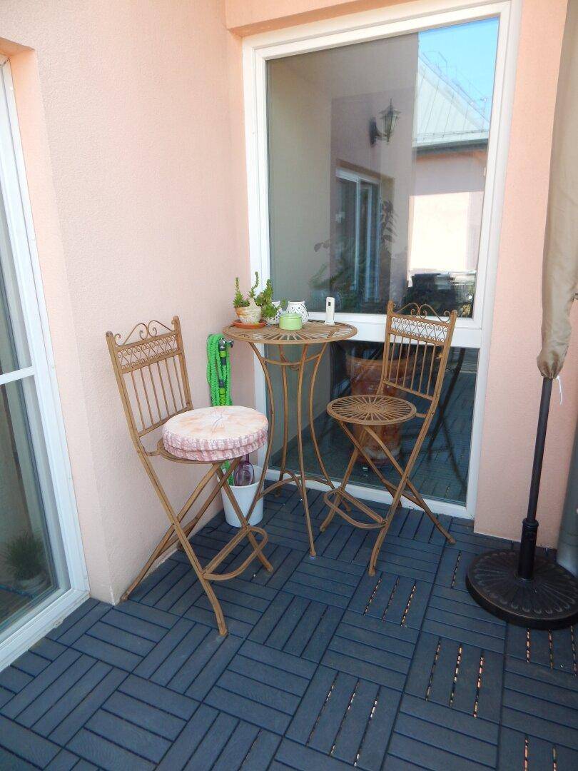 Gemütlicher Balkon mit Bistrotisch, Stühlen und Blick auf die Umgebung.