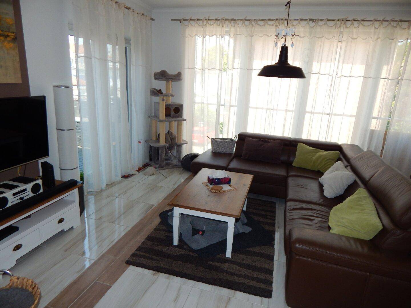 Gemütliches Wohnzimmer mit Ledersofa, Couchtisch und viel Tageslicht.
