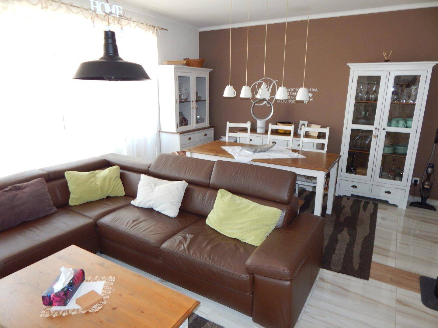 Offener Wohn- und Essbereich mit Ledersofa und Holztisch.