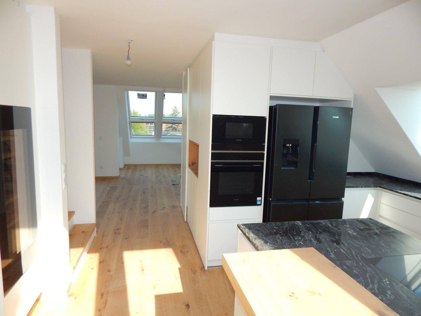 Offener Küchenbereich mit modernen Einbaugeräten und Blick in den angrenzenden Wohnraum.