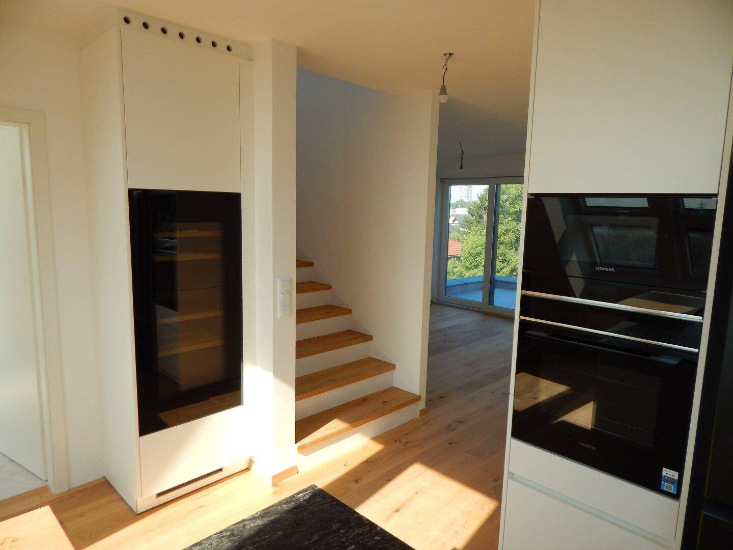 Heller Flurbereich mit Holztreppe und integriertem Schrank, der zu weiteren Räumen führt.