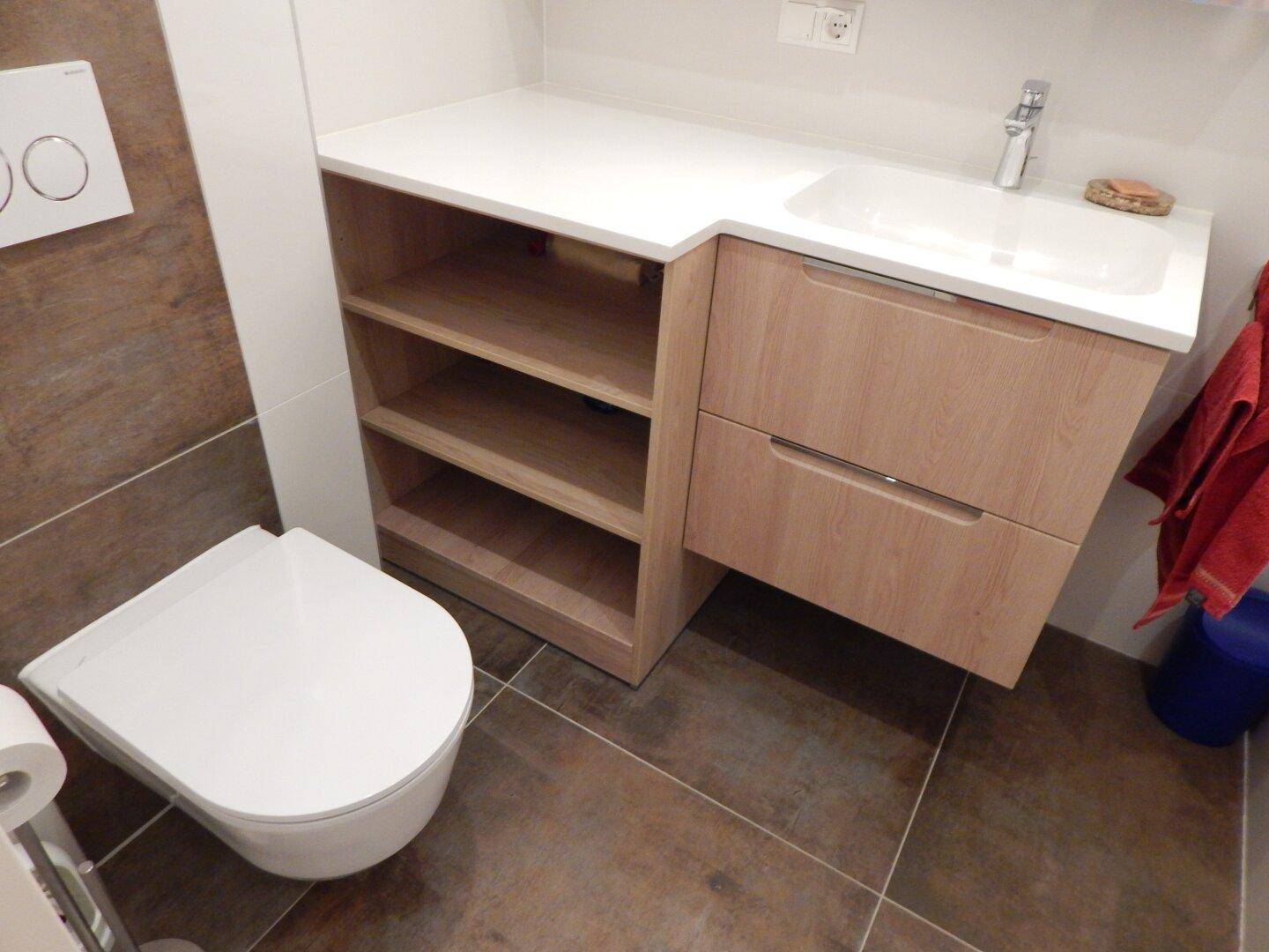 Modernes Badezimmer mit Wand-WC, Waschbecken und praktischem Unterschrank mit Ablageflächen.