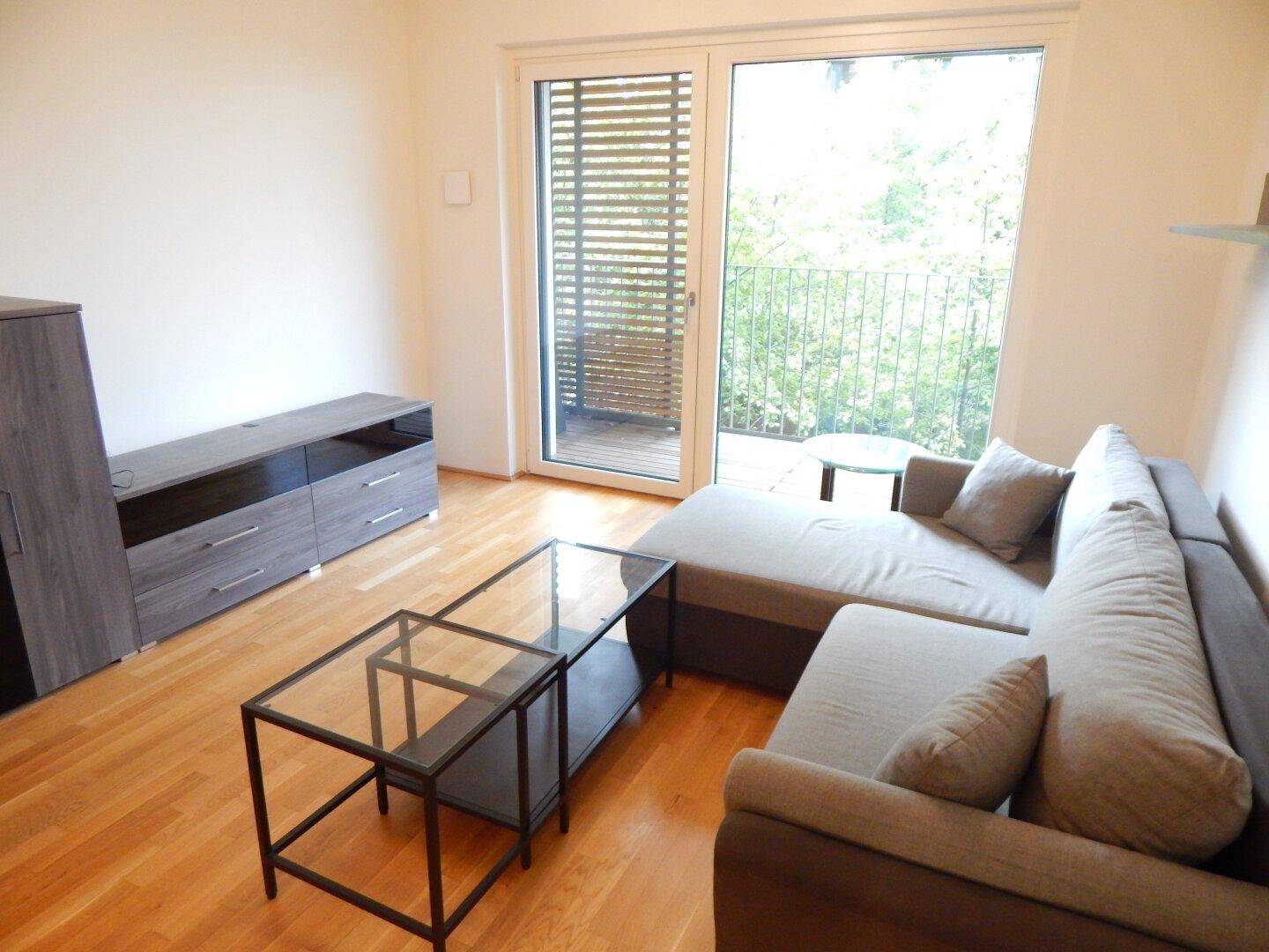 Gemütliches Wohnzimmer mit Ecksofa, Couchtisch und hellem Parkettboden.