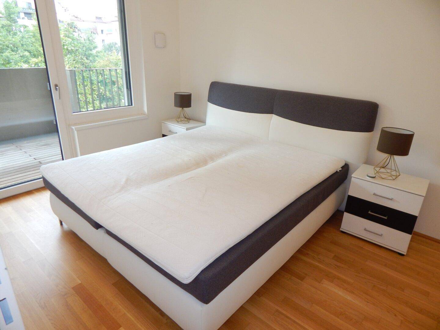 Helles Schlafzimmer mit großem Bett, Nachttischen und direktem Balkonzugang.