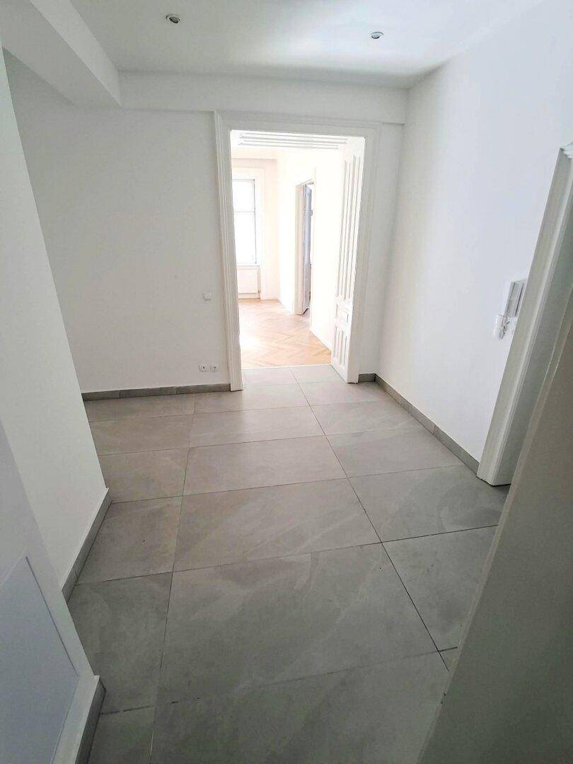 Heller Flur mit modernen grauen Fliesen und Zugang zu weiteren Räumen der Wohnung.