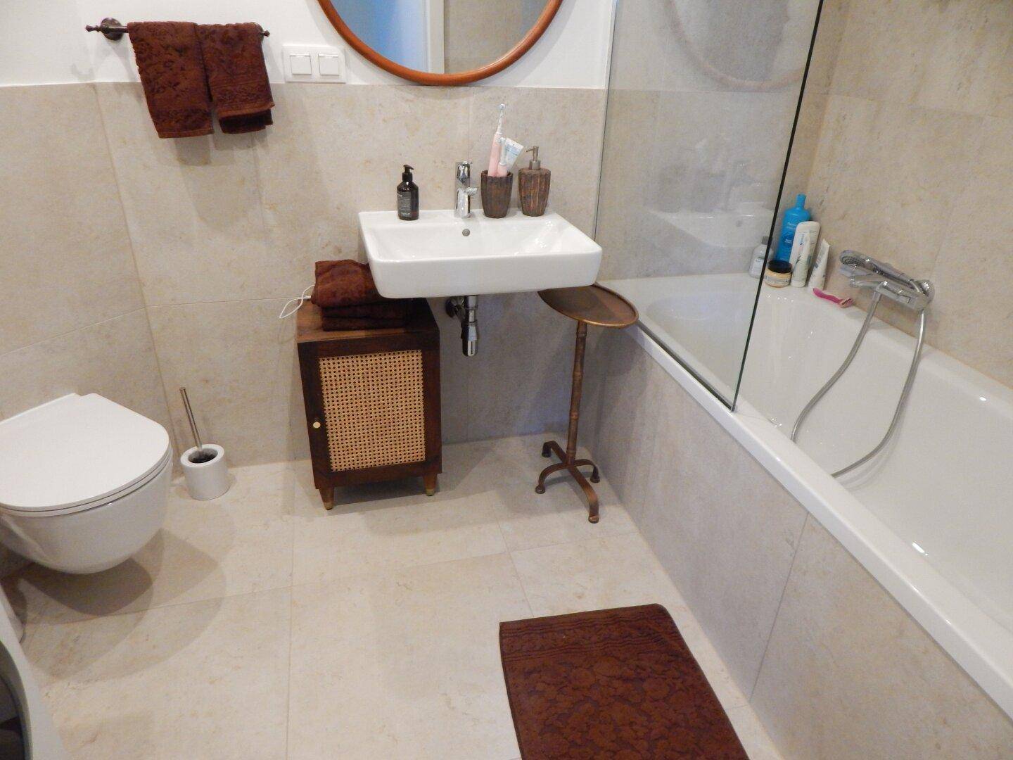 Modernes Badezimmer mit Badewanne, wandhängendem WC und Einzelwaschbecken, gefliest.
