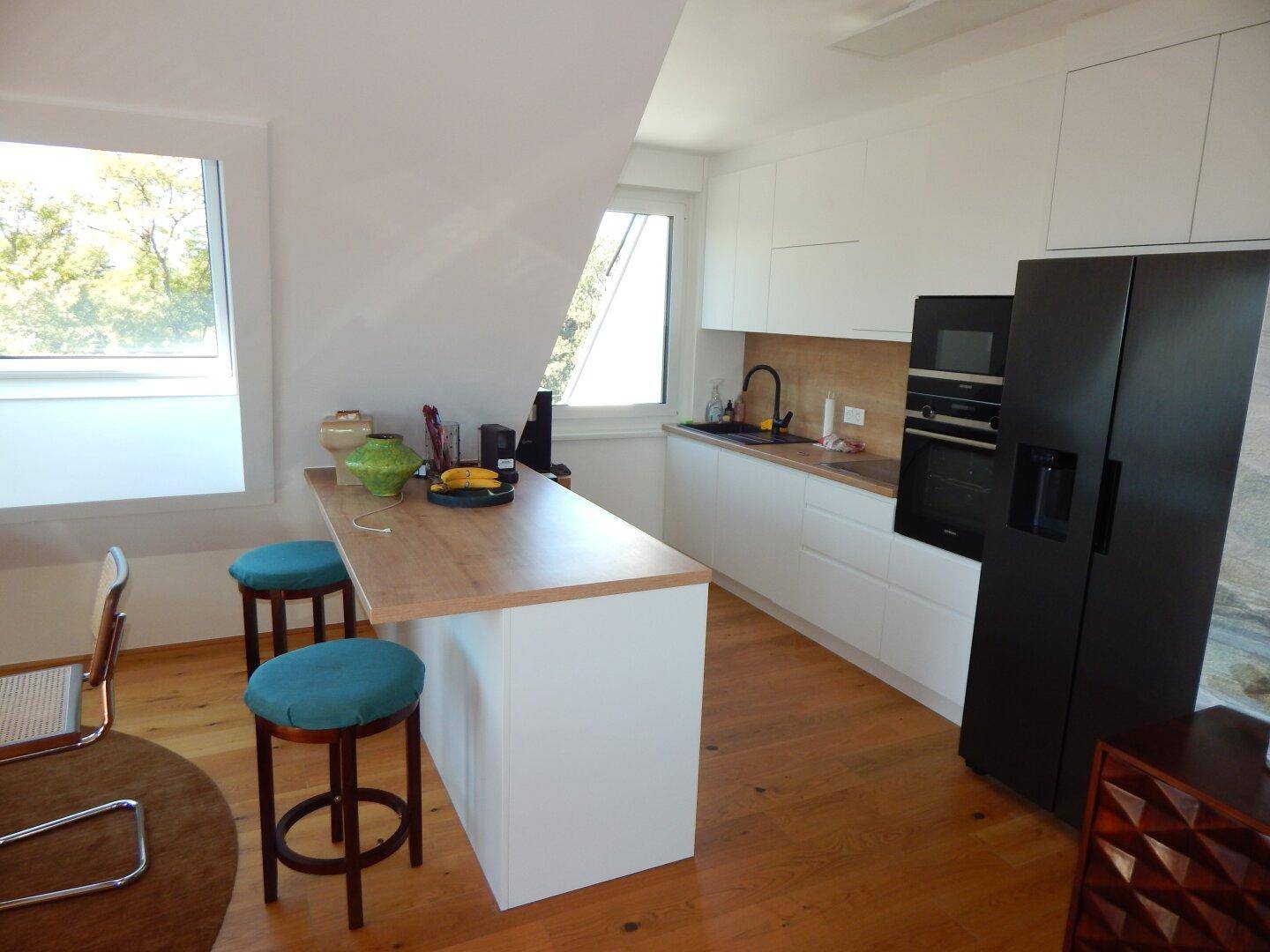 Moderne Einbauküche mit weißen Fronten, Holzarbeitsplatte und integrierter Frühstücksbar.