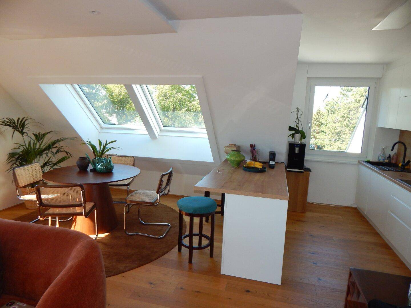Essbereich und moderne Küche mit Frühstücksbar, hell durch große Fenster und Dachfenster.