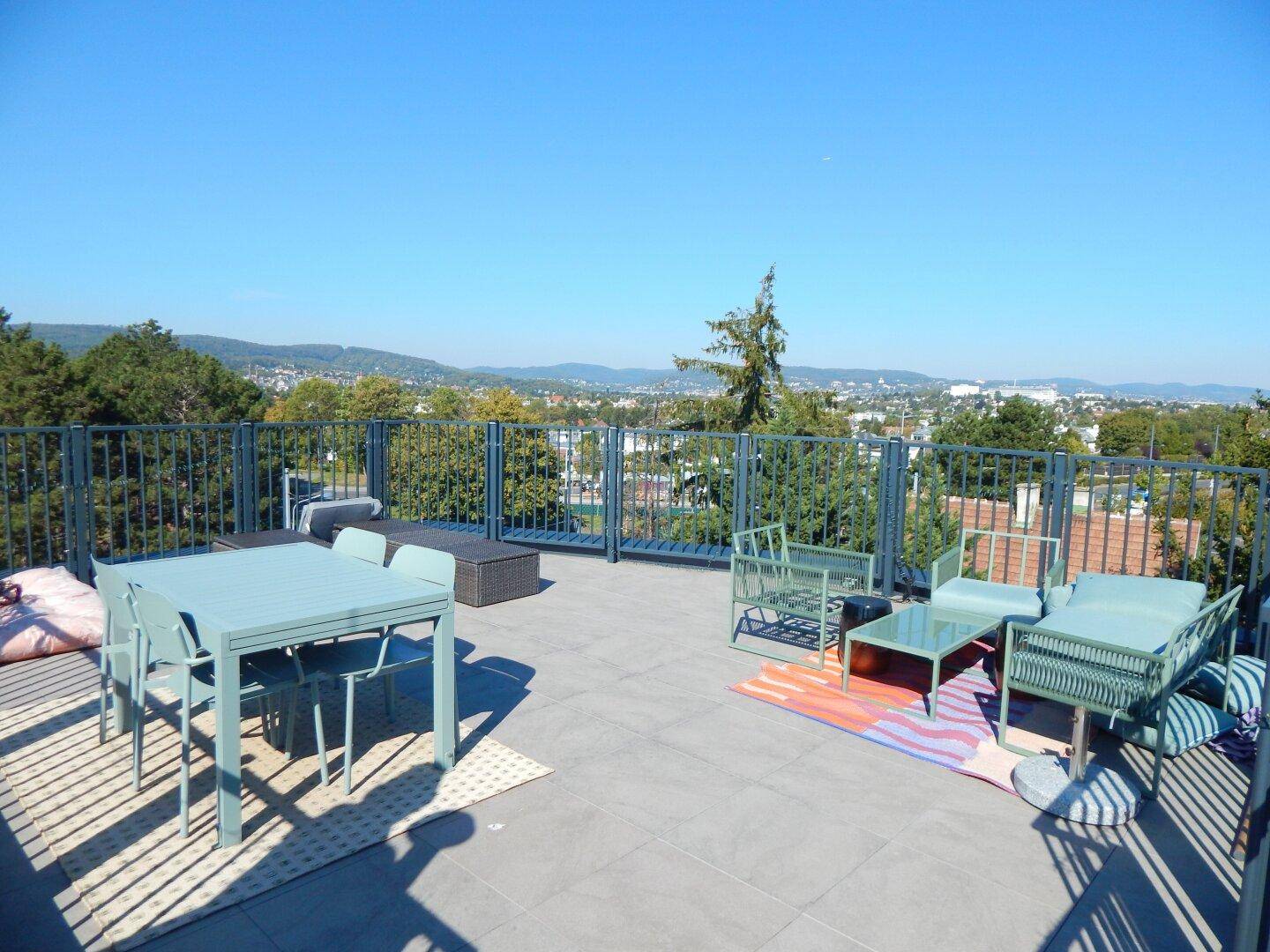 Geräumige Dachterrasse mit Ess- und Lounge-Bereich sowie weitem Blick über die Stadt und Berge.