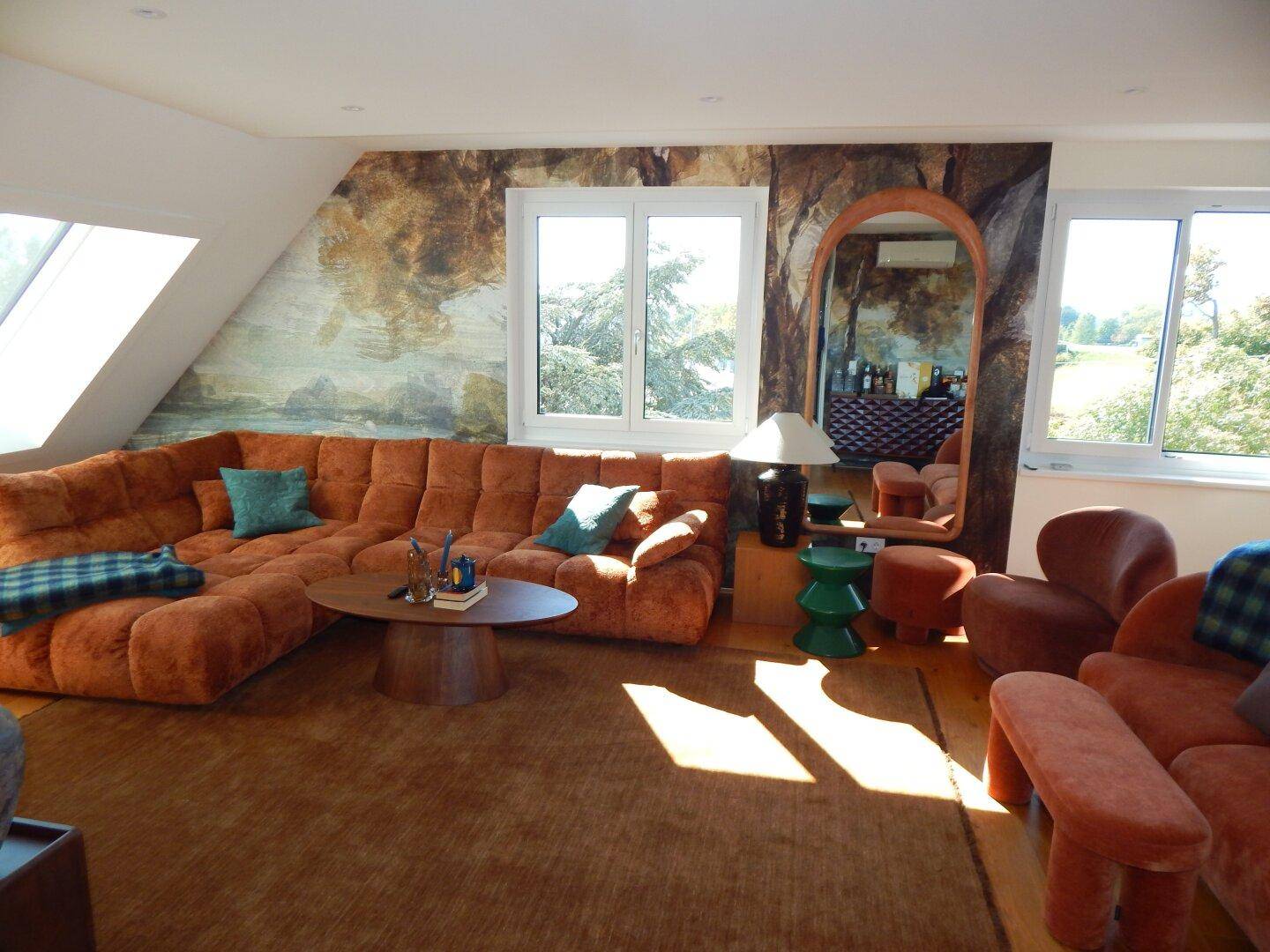 Geräumiges Wohnzimmer mit bequemen Sofas, Holzboden und viel natürlichem Licht durch Dachfenster.